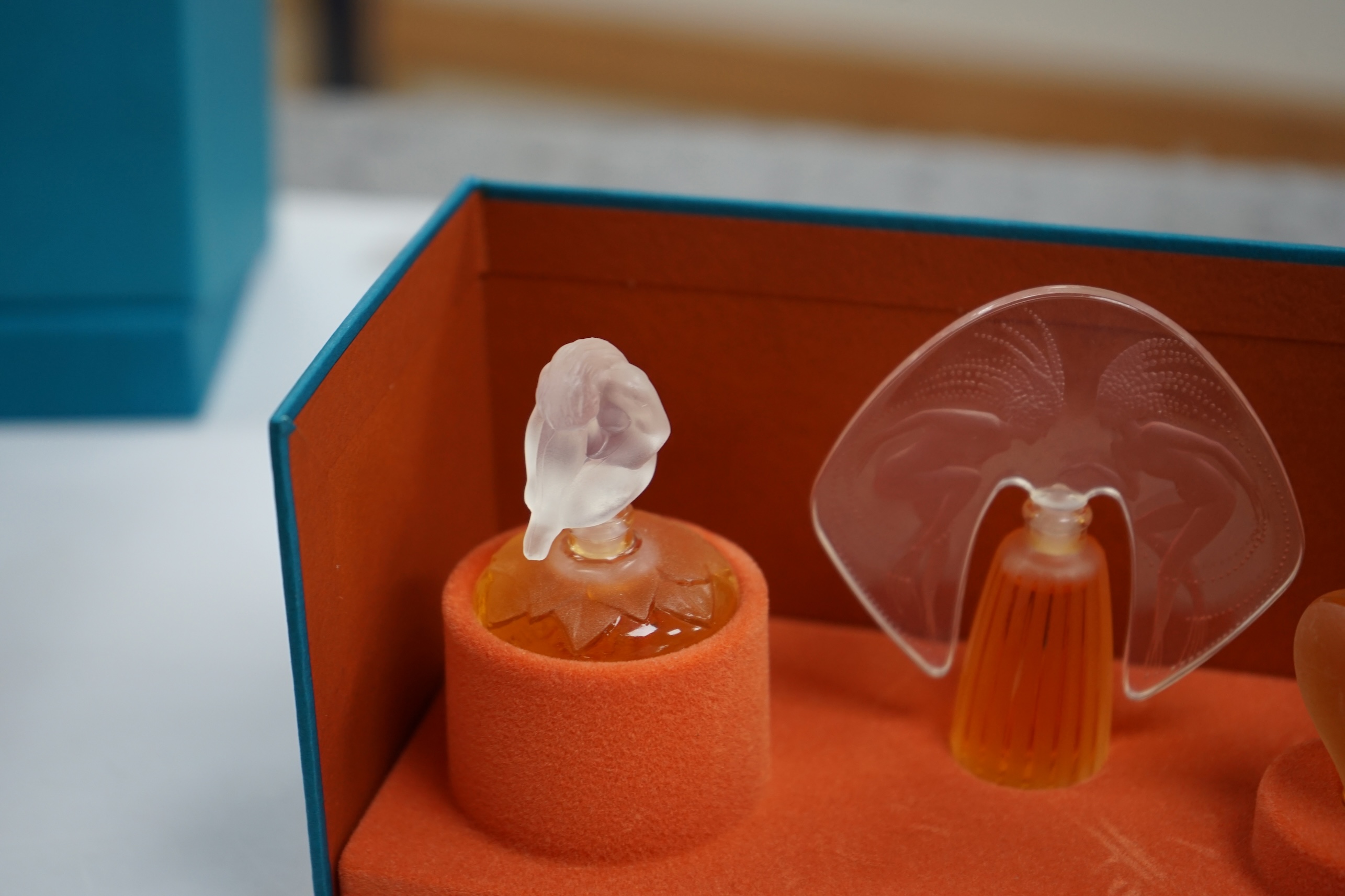 Two Lalique sets of three miniature perfume bottles. 'Les flacons miniatures' 1996-1997 and 1998-2000, boxed and sealed, tallest 7cm high. Condition - good